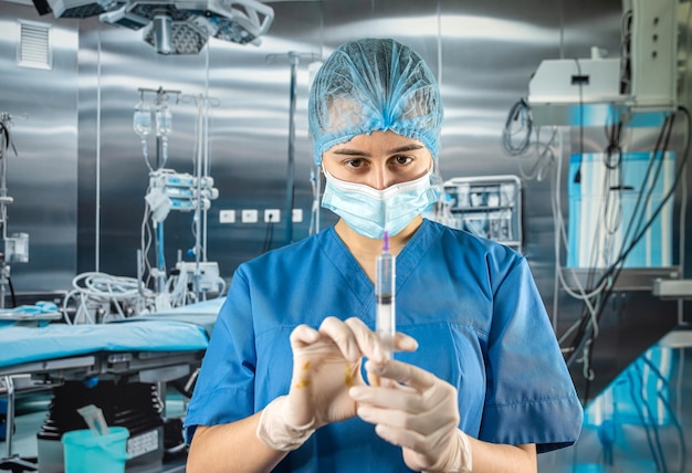 Médico segurando a seringa e preparando-se antes de receber o paciente no hospital moderno da sala de operação