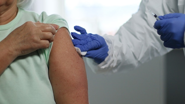 Médico segurando a seringa e usando algodão antes de aplicar a injeção no paciente. Vacinação e prevenção contra gripe ou pandemia de vírus.