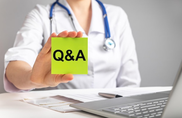 Médico segurando cartão com letras qa FAQ em medicina e conceito de saúde Mulher de jaleco respondendo a perguntas de pacientes on-line
