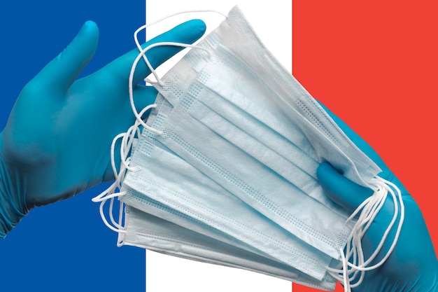 médico segurando máscaras médicas nas mãos, luvas azuis no conceito de fundo da bandeira nacional da França