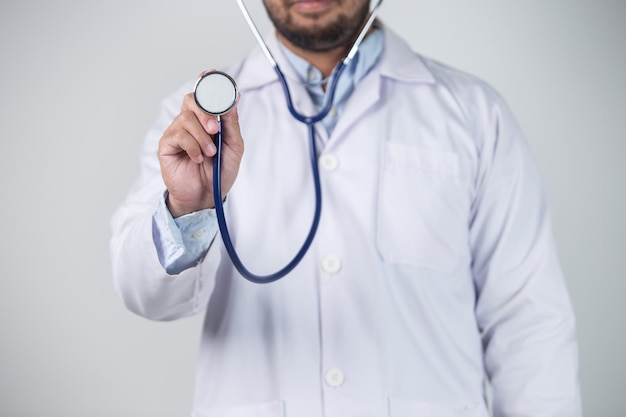 Médico segurando o estetoscópio em fundo cinza Conceito médico e de saúde