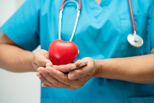 Médico segurando um coração vermelho na enfermaria do hospital conceito médico forte saudável