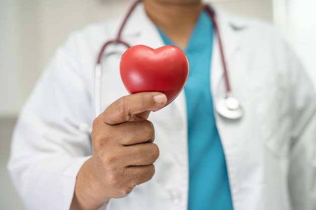 Médico segurando um coração vermelho na enfermaria do hospital conceito médico forte saudável