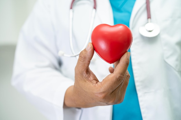 Médico segurando um coração vermelho na enfermaria do hospital conceito médico forte saudável