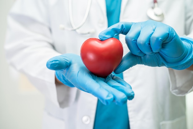 Médico segurando um coração vermelho na enfermaria do hospital conceito médico forte saudável