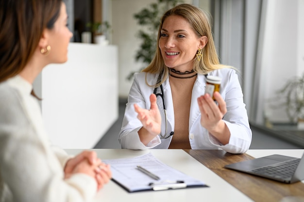 Médico segurando um frasco de comprimidos e guiando o paciente com instruções de dosagem e clínica de uso de medicamentos