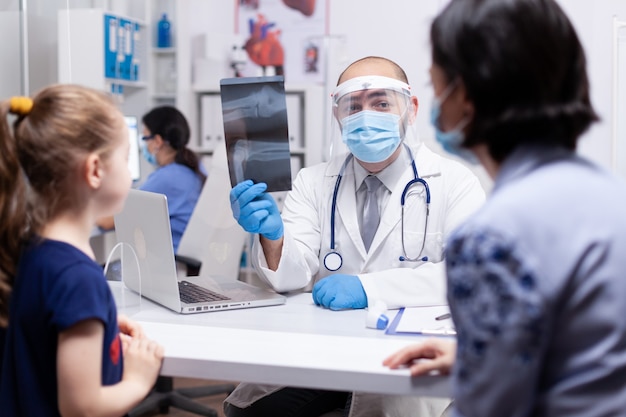 Médico segurando um raio-x de um paciente usando máscara facial contra coronavírus espesso durante a pandemia global