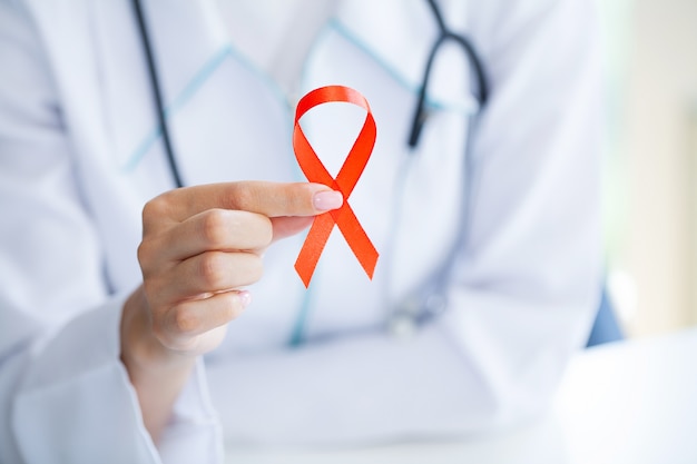Médico segurando uma fita vermelha pedindo sexo seguro e proteção contra a Aids