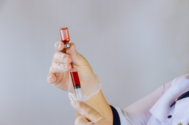 Médico segurando uma garrafa de sangue de diluição de seringa em local de trabalho médico com injeção