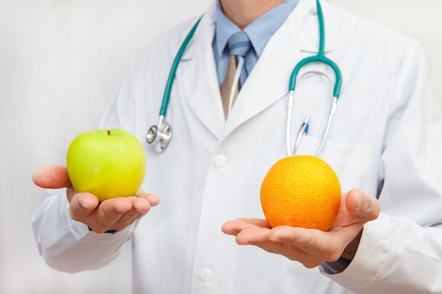Médico segurando uma maçã e uma laranja