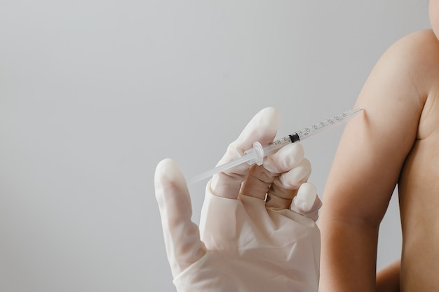 Médico segurando uma seringa de vacina subcutânea para uma criança no consultório médico