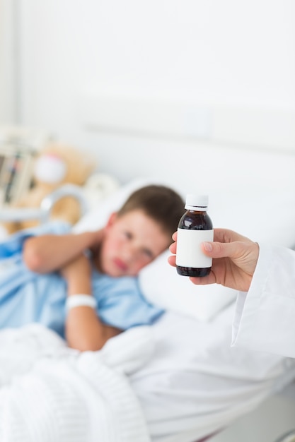 Médico segurando xarope contra a tosse com menino no hospital