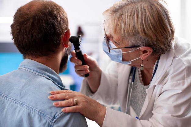 Médico sênior examina a orelha do paciente