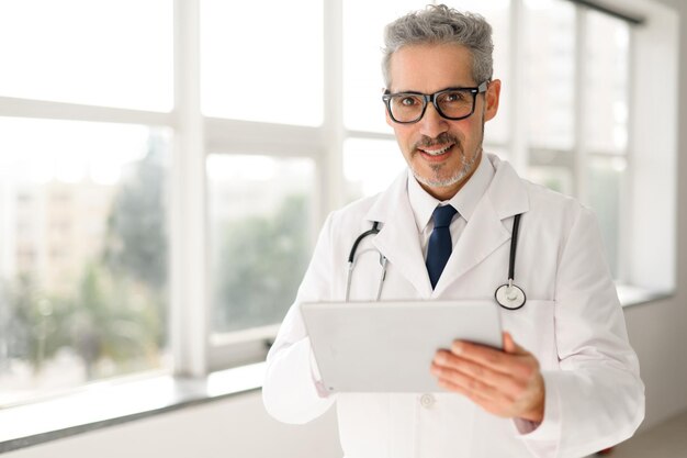 Médico sênior experiente, confiante e de cabelos grisalhos a usar comprimidos.