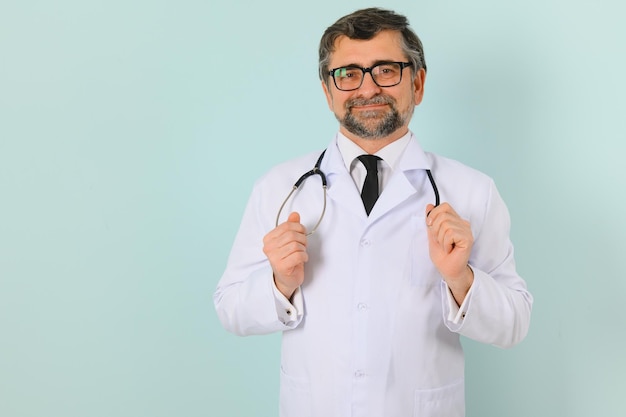 Médico senior sonriente con un estetoscopio Sobre un fondo azul El concepto de la victoria de la humanidad sobre la enfermedad