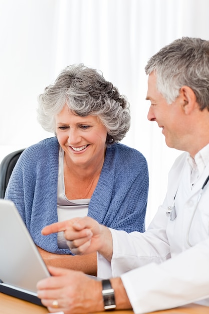 Un médico senior con su paciente mirando la computadora portátil