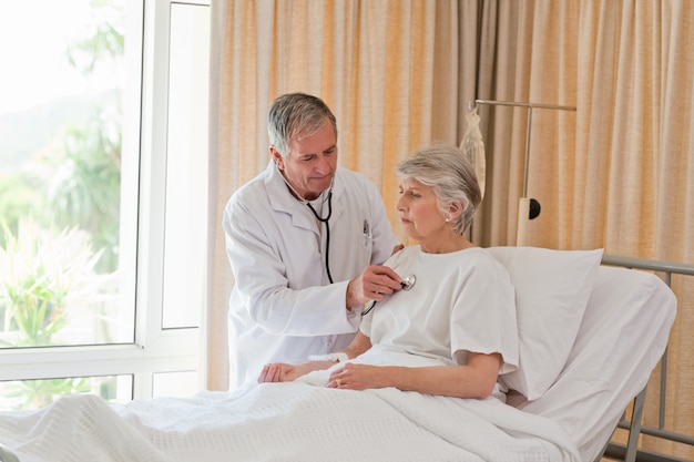 Médico Senior tomando el latido del corazón de su paciente