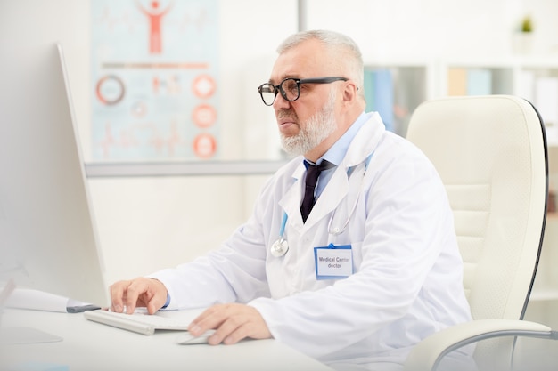 Médico sênior, usando o computador no trabalho