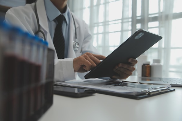 Médico sentado en el escritorio y escribiendo una receta para su paciente