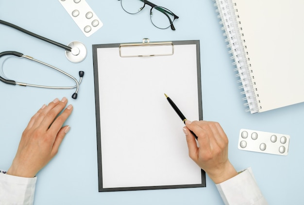 Médico sentado na mesa de escritório azul e trabalhando