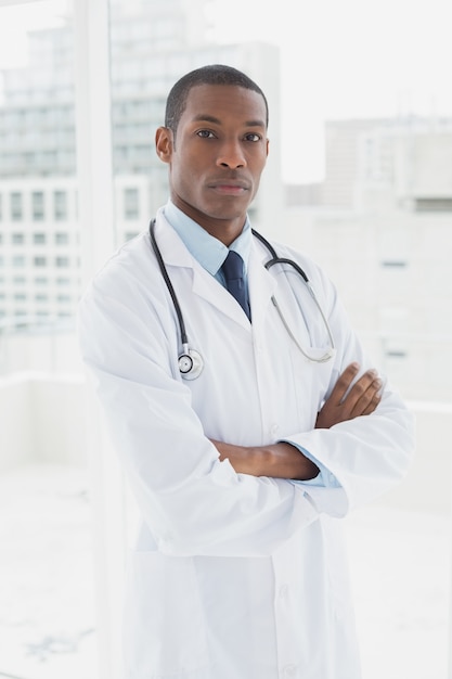 Médico serio con los brazos cruzados en una oficina médica