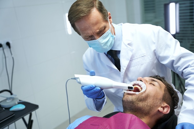 Médico sério curando os dentes de um paciente do sexo masculino