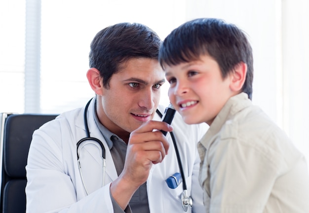 Médico serio examinando las orejas del niño pequeño