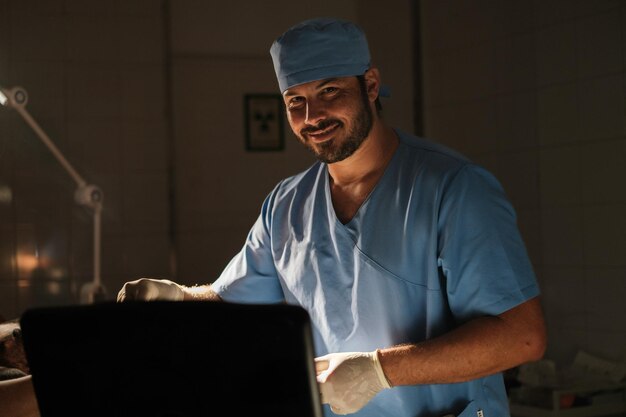 Médico sonriente mirando a la cámara mientras realiza una ecografía con poca luz