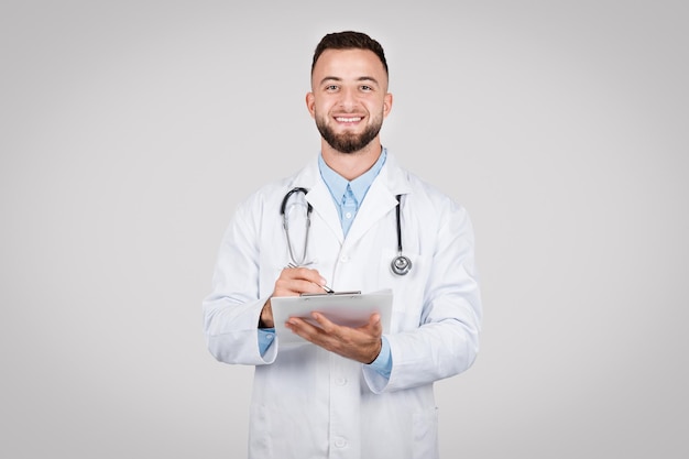 Un médico sonriente con un portapapeles y un estetoscopio