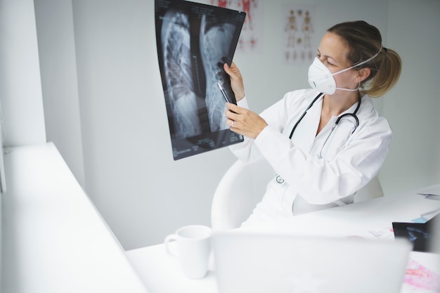 Médico sonriente sosteniendo una radiografía médica en la clínica