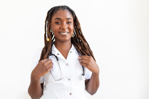 Médico sorridente confiante posando e olhando para a câmera com estetoscópio nas mãos amigável médica afro-americana sorridente médico com estetoscópio no pescoço