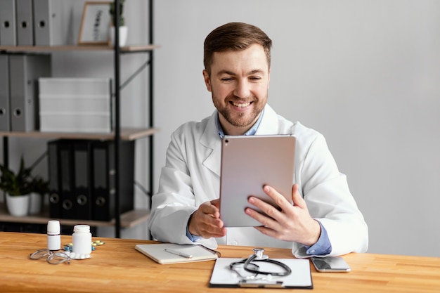 Foto médico sorridente de tiro médio segurando tablet