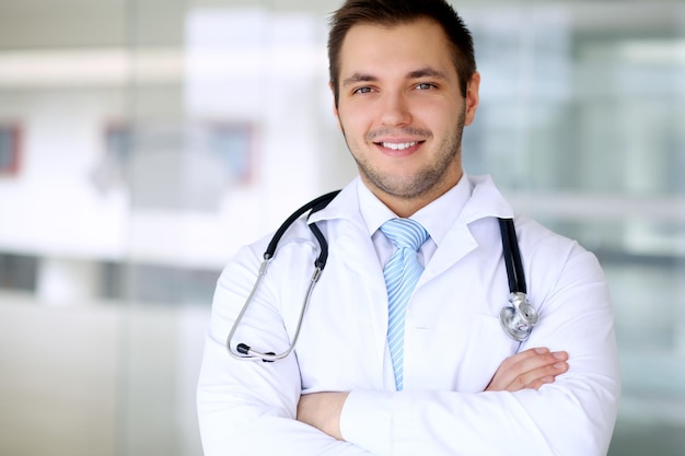 Médico sorridente esperando por sua equipe em pé