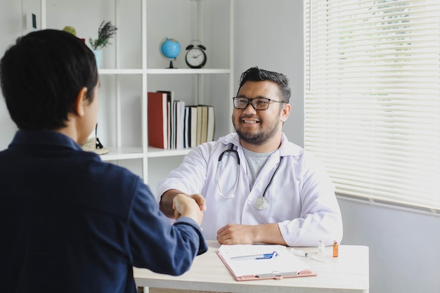 Médico sorridente feliz cumprimenta seu paciente apertando as mãos