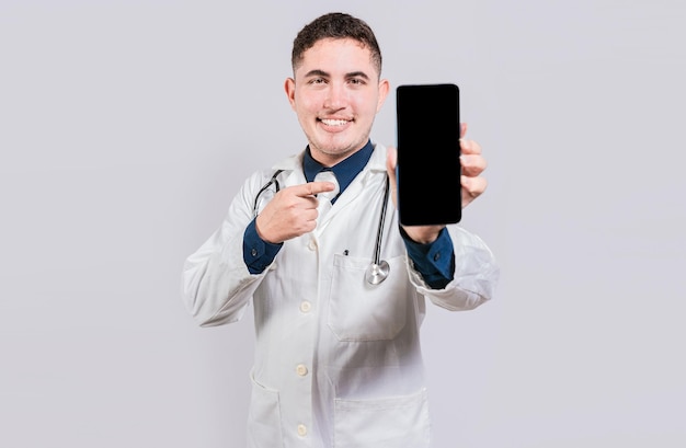 Médico sorridente mostrando um aplicativo na tela do celular Jovem médico feliz mostrando a tela do celular isolada