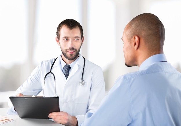 Foto médico sorrindo com paciente do sexo masculino sentado à mesa