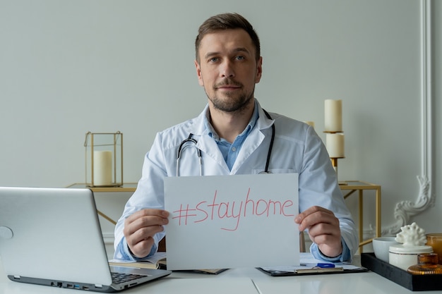 Médico sosteniendo un cartel de quedarse en casa durante una epidemia de coronavirus