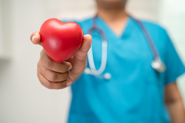 Foto médico sosteniendo un corazón rojo en la sala del hospital saludable fuerte concepto médico