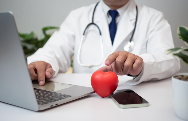 Un médico sosteniendo y mostrando un corazón rojo en la oficina del hospital Atención médica y concepto de servicio de personal médico