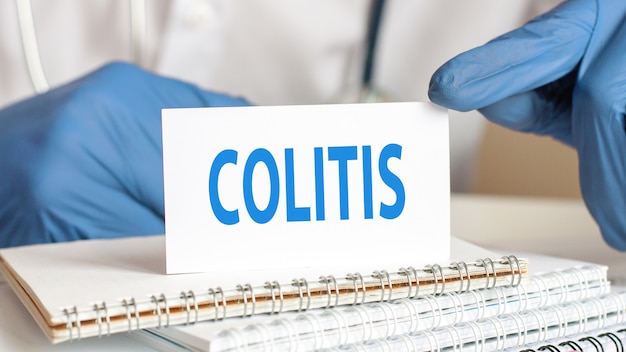 Médico sosteniendo una tarjeta de papel blanco con texto: colitis