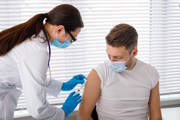 El médico sostiene una jeringa antes de inyectar a un paciente con una máscara médica Covid19 o vacuna contra el coronavirus