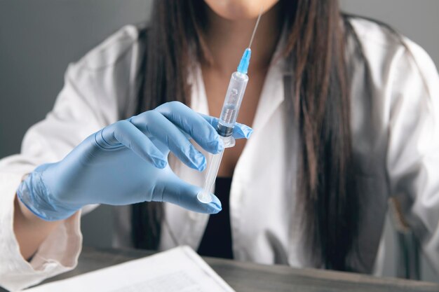 El médico sostiene una jeringa junto a la mesa.