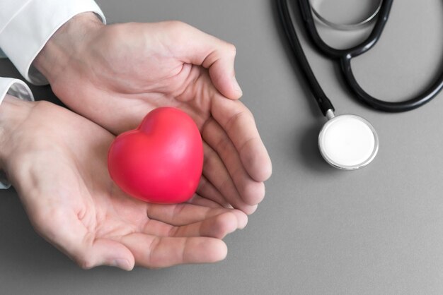 Foto el médico sostiene las manos y da masaje rojo al corazón del paciente para recuperarse de la enfermedad el concepto de hospital y atención médica de rcp y cardiología de ataque cardíaco y enfermedad la donación de corazón y la rehabilitación