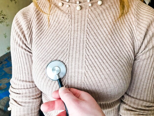 El médico sostiene en su mano un estetoscopio médico, un fonendoscopio y escucha el corazón del pecho.