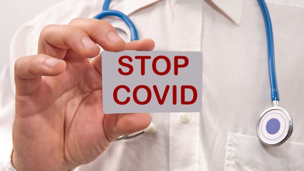 El médico sostiene una tarjeta con el texto stop covid en su mano