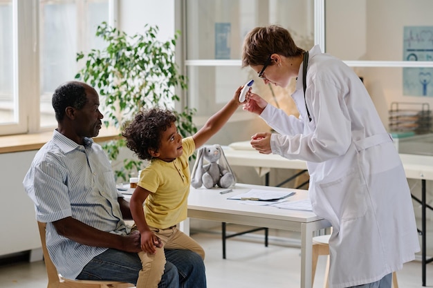 Médico tentando examinar criança na clínica