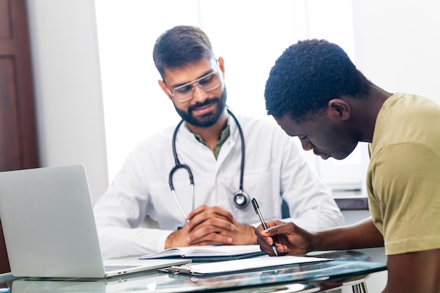 Médico terapeuta indiano em consultoria de jaleco branco apoiando paciente em hospital de clínica moderna