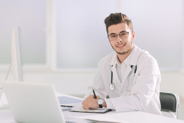 médico terapeuta sentado en una mesa en su oficina.