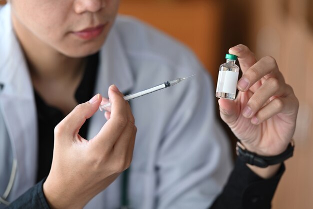 Médico tiro recortado segurando a seringa e o frasco da vacina. Conceito de medicina e saúde.