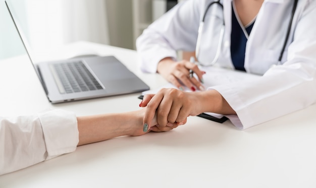 Foto el médico se toma de las manos para consolar y alentar al paciente.